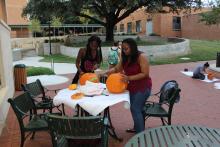 Students carving pumpkins on a table