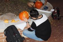 Students carving pumpkins at night