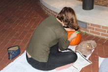 Student carving a pumpkin at night