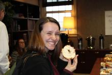 A student smiling and holding a bagel