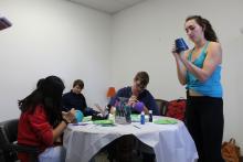 Several students painting pots around a table