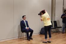 A student in a suit getting his photo taken in the ballroom
