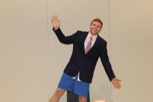 Bryan posing for the camera wearing a suit top and blue shorts on bottom
