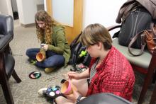 A couple of students sitting on the floor and painting their pots