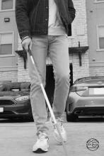 Black and white photo of a person walking with a cane.