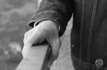 Black and white photo of a hand holding a railing.
